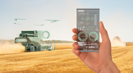 Farmer uses a futuristic smartphone to control autonomous harvester. Smart farming concept
