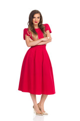 Beautiful Woman In Elegant Red Dress And Gold High Heels Is Standing With Arms Crossed