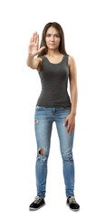 Young beautiful woman in gray sleeveless top and blue jeans standing and holding right hand out in stop gesture isolated on white background.