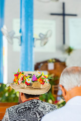 Woman in a hat in a catholic church in the service, Rarotonga, Aitutaki, Cook Islands. With selective focus. Back view. Vertical.