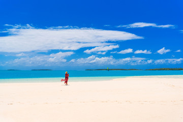 Fototapeta na wymiar Woman in red dress on a sandbank with turquoise water, Aitutaki island, Cook Islands, Copy space for text...