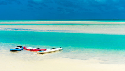 Surfboard on sandy beach, Aitutaki island, Cook Islands, South Pacific. Copy space for text.