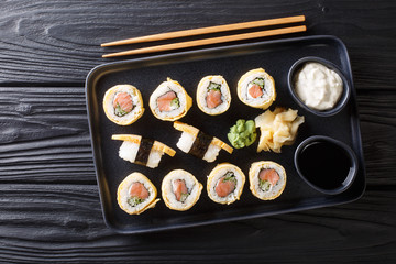 Tamagoyaki sushi roll with rice, cheese, salmon and avocado closeup on a plate. Horizontal top view