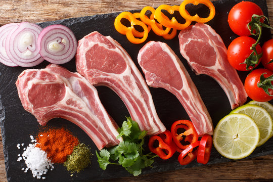 Fresh raw lamb chops on the bone with vegetable ingredients close-up. horizontal top view 