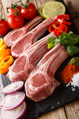Fresh raw lamb chops on the bone with vegetable ingredients close-up. vertical