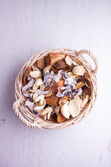 VISTA SUPERIOR DE CESTA DE MIMBRE CON FLORES SECAS EN FONDO DE MADERA CLARA