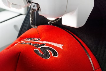 Close up picture of sport cap and embroidery machine