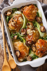 chicken thighs with baby bok choy, shiitake mushrooms and cheese sauce in a rustic style close-up. vertical top view from above - obrazy, fototapety, plakaty