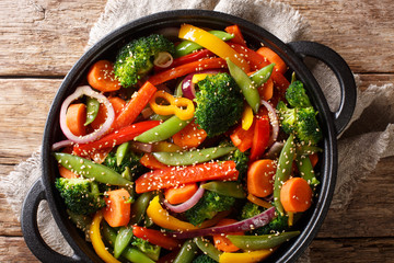 Stir fry of vegetables with sesame close-up in a bowl on the table, rustic. horizontal top view