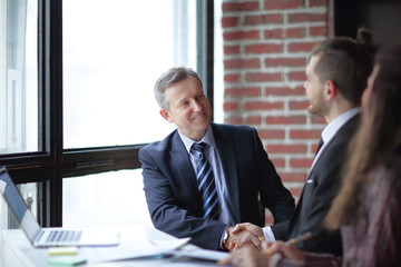 friendly handshake of business partners sitting at a Desk