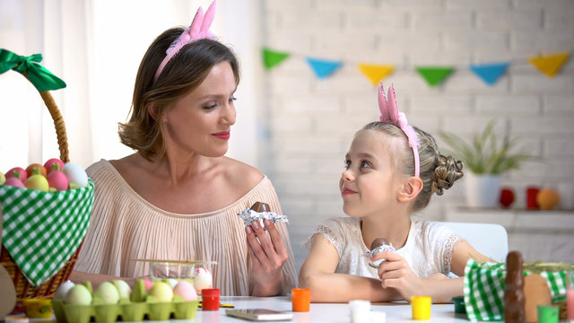 Beautiful Mother And Daughter In Funny Headbands Eating Easter Chocolate Eggs