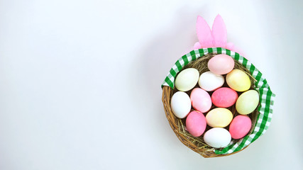 Colored Easter eggs in basket standing on table, headband with pink bunny ears
