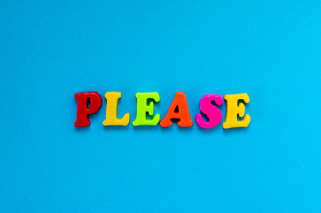 word please from plastic magnetic letters on blue background