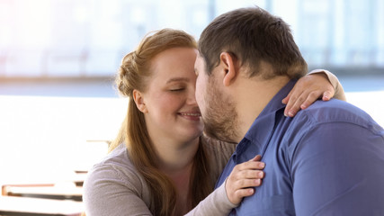 Sweet couple in love nuzzling sitting on city bench, weekend together, closeness