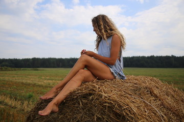 Naklejka na ściany i meble girl in a field on the background of hay