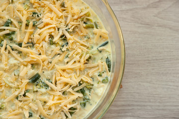 Vegetable mix for casserole. Broccoli, cauliflower, green beans and gravy prepared for baking. Shredded cheese on the surface of the casserole. Cooking healthy food from vegetables.