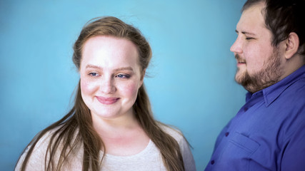 Obese couple feeling happy together, tender relationships, blue background