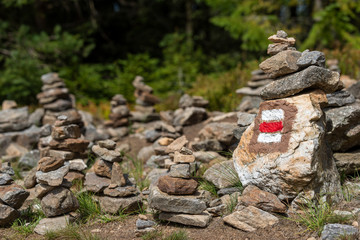 Hiking trail sign mark painted on a rock in stack of zen stones. Path leading trough the beautiful Bohemian Forest National Park. Trekking concept background.