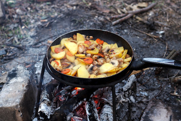 Potatoes with vegetables in a frying pan, cooking food in a hike