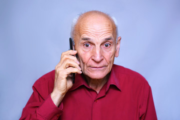 elderly mature man talking on the phone, surprised and indignant look