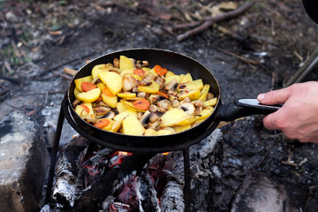 Potatoes with vegetables in a frying pan, cooking food in a hike