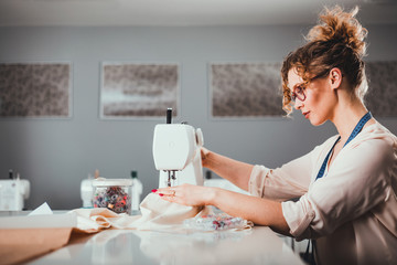 Tailor during work using sewing machine, fashion designer at workshop
