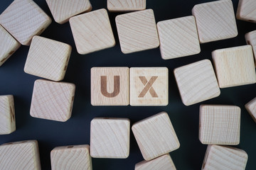 User Experience, UX design, usability test or research concept, flat lay or top view of wooden cube block with alphabets building the word UX and other random block on blackboard background