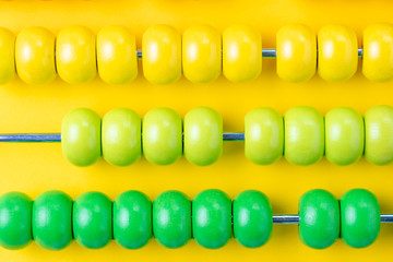 Colorful wooden abacus beads on vivid yellow background, business financial or accounting profit and loss concept, or use in education school maths and arithmetic symbol