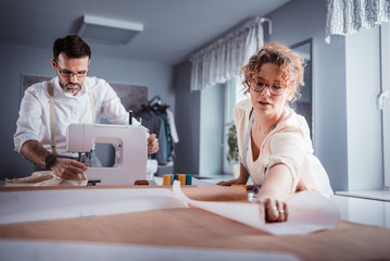 Obraz premium Professional tailors during work on project using sewing machine at fashion design studio