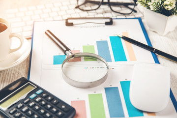 magnifier with calculator  on graph on office desk
