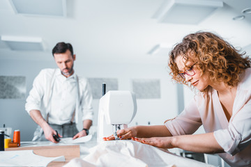 Obraz premium Professional tailors during work on project in fashion design studio, using sewing equipment