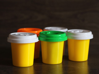 Yellow plastic bottles with colorful lids on wooden background