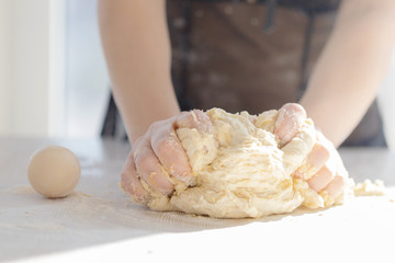 Woman's hands knead the dough close up