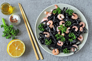 Black noodles with shrimps and greens. Black food. Vegetarian trend lunch.