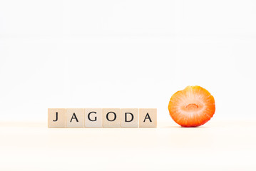 Wooden letters form the Croatian word Jagoda, which means strawberry. Next to it is a freshly cut...