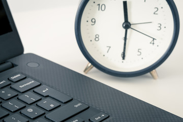  computer and an alarm clock measuring the time running away. The concept of urgent deadlines at work and commitments