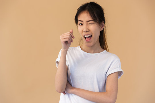 Photo of cute korean woman wearing basic t-shirt smiling and winking at you