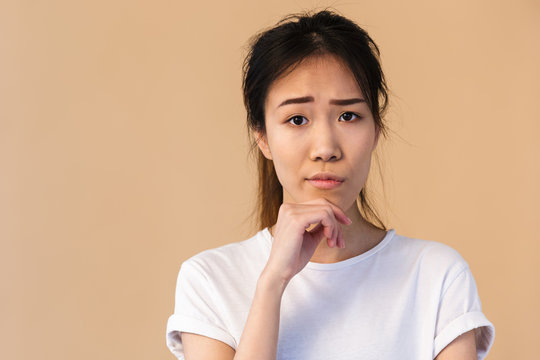 Photo of young japanese woman wearing basic t-shirt touching chin and looking at camera