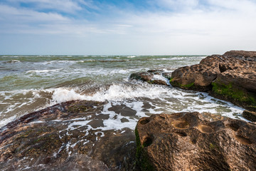 Fototapeta na wymiar Splash of waves on a rocky seashore