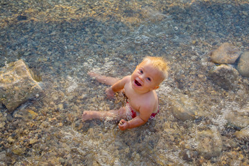 Cute child, toddler boy, enjoying the sunset over a lake