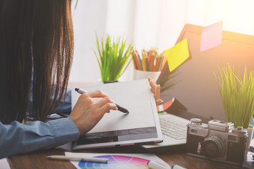 Young cute Graphic designer using graphics tablet to do his work at desk