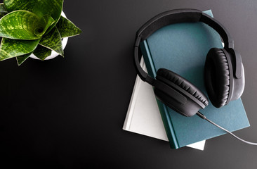 audiobook concept with overhead shot of headphones on stack of books on black background
