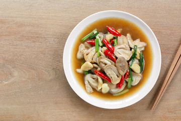 top view of stir fried straw mushroom with oyster sauce in a ceramic dish on wooden table. asian homemade style food concept.