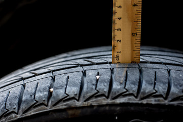 Close up wood ruler measure the tread of black tire