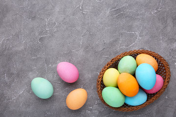 Colorful easter eggs in basket on grey background