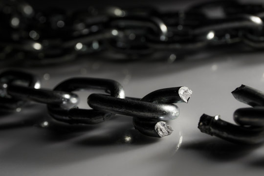 Broken chain on white surface, selective focus shallow depth of field