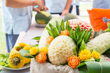 Fruit carving art, in preparation process with blurry artist in the background
