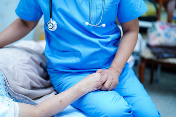 Asian nurse physiotherapist doctor care, help and support senior or elderly old lady woman patient lie down in bed at hospital ward : healthy strong medical concept.