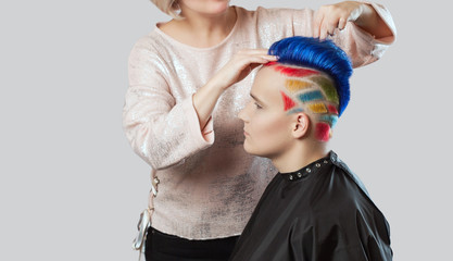 Hairdresser makes hairstyle.Portrait of a beautiful young teenager with a beautiful creative hairstyle, hair painted blue, yellow and red.