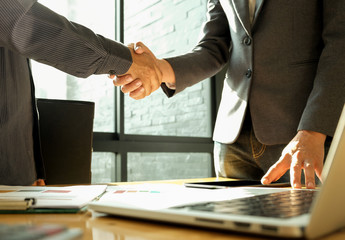 Two businessmen join hands after reaching a business agreement.